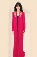 Elegant crimson pleated gown with gold embroidery and structured shoulders, perfect for formal occasions.