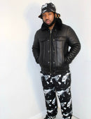 Man wearing a black leather jacket and abstract print joggers, showcasing urban streetwear style.