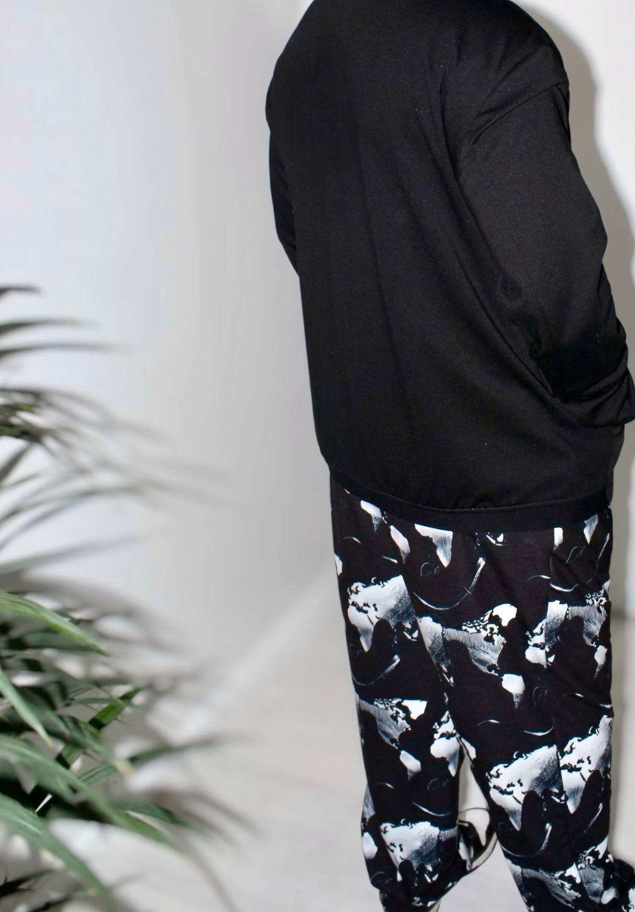 Back view of model wearing Midnight Silver Eclipse Wide-Leg Joggers with abstract print and black sweatshirt.