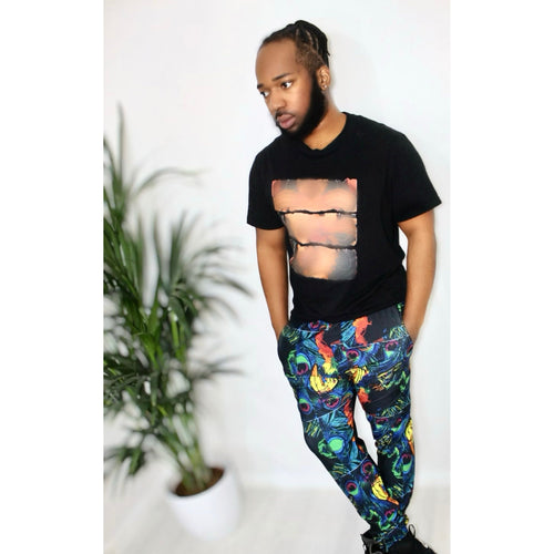 Urban Peacock Mirage Joggers featuring vibrant geometric print, styled with a black tee, in a modern urban setting.